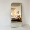 Brushed gold rounded rectangle full length mirror leaning against a white wall Rounded Rectangle Full Length Mirror