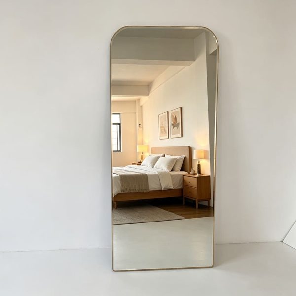 Brushed gold rounded rectangle full length mirror leaning against a white wall Rounded Rectangle Full Length Mirror