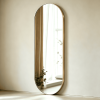 Gold oval full length mirror leaning against a wall in a minimalist interior Oval Full Length Mirror